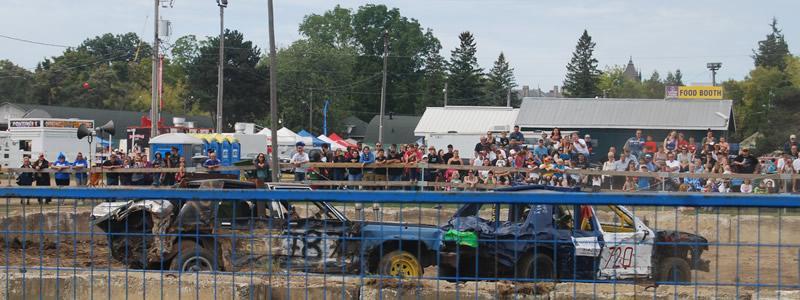 Demolition cars in competition with spectators looking on.